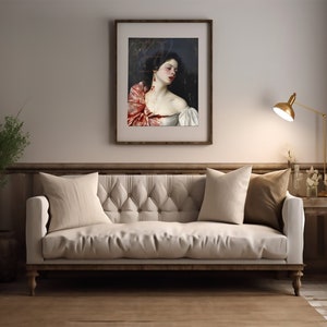May include: A white sofa with two pillows, one beige and one brown, sits in a room with a framed painting of a woman with a red scarf. A gold lamp is on a side table to the right of the sofa.