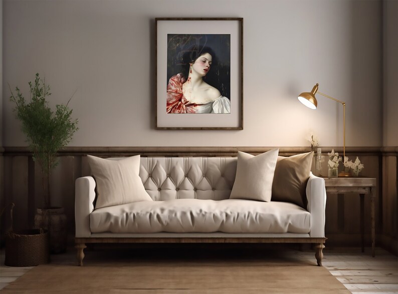 May include: A white sofa with two pillows, one beige and one brown, sits in a room with a framed painting of a woman with a red scarf. A gold lamp is on a side table to the right of the sofa.