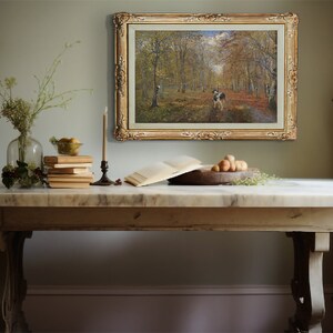 May include: A rustic wooden table with a white marble top. A framed painting of a forest scene hangs on the wall behind the table. A vase of flowers, a stack of books, and a bowl of fruit are on the table.
