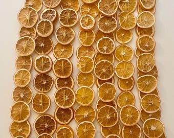 May include: Overhead shot of numerous dried orange slices arranged in vertical rows. The slices vary in color from light tan to deep brown, with visible textures and patterns. The image is well-lit, highlighting the natural colors and details of the dried fruit.