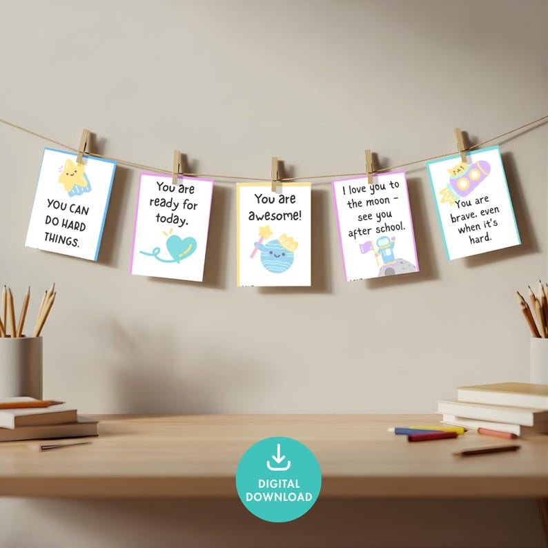 May include: A string of five colorful cards with positive affirmations, clipped to a string with wooden clothespins. The cards have illustrations of a star, heart, planet, astronaut, and rocket ship, with encouraging phrases.