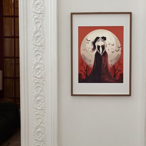May include: A framed illustration of two women in red dresses standing together under a full moon. The background is a red and orange sky with bats flying around the moon.