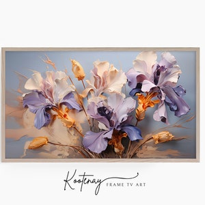 Puede incluir: Una pintura enmarcada de un ramo de iris púrpuras, blancas y naranjas sobre un fondo azul claro. La pintura está en un marco de madera clara. La firma del artista, "Kootenay", es visible en la esquina inferior derecha de la pintura.