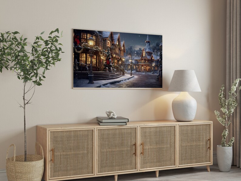 May include: A wooden cabinet with three doors and woven rattan panels. The cabinet is decorated with a framed print of a snowy village scene with a lamp on the top.