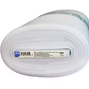 May include: A large roll of white Pellon 985F Sandwich Fuse 2-Sided Fusible Fleece. The label specifies 100% polyester, machine wash warm, tumble dry medium or dry clean, and indicates 30 yards of material. The roll is wrapped in clear plastic.