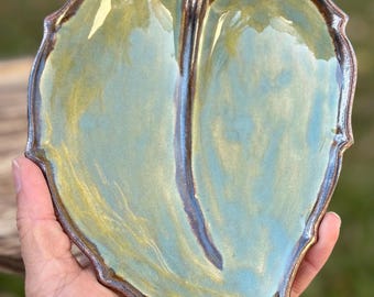 May include: A ceramic leaf-shaped dish with a green glaze and brown accents. The dish is glazed with a glossy finish.