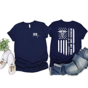 May include: Navy blue t-shirts with white graphics. One shirt has "ICU" and a heartbeat line. The other features an American flag design with a medical symbol and the text "Intensive Care Unit Nurse".