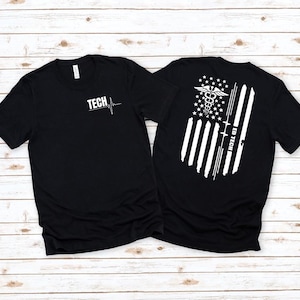 May include: Black t-shirts with white graphics. One shirt has "TECH" and a heartbeat line. The other shirt features a medical caduceus, stars, stripes, and the text "ED TECH" in a flag design. Both shirts are short-sleeved.