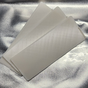 May include: Three white rectangular plastic sheets stacked on top of each other. The sheets are smooth and have a subtle texture.
