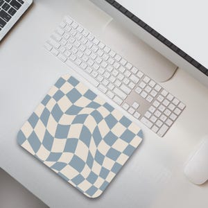 May include: A blue and cream checkered mouse pad with a wavy pattern. The mouse pad is on a white desk with a keyboard and a computer monitor.