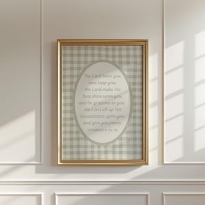 May include: A framed wall art print featuring a sage green and white gingham pattern background. Centered is an oval shape containing the text: The Lord bless you and keep you; the Lord make His face shine upon you, and be gracious to you; the Lord lift up His countenance upon you, and give you peace. NUMBERS 6:24-26.