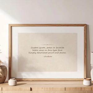 May include: A rectangular wooden frame containing a beige print with dark text that reads: Custom quote, poem or favorite bible verse in this type font. Simply download print and frame. -Author. The frame is displayed on a wooden surface.
