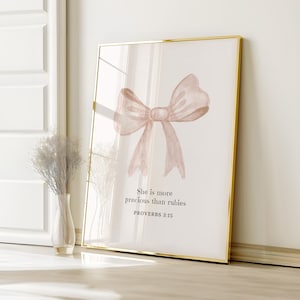 Puede incluir: Una pintura de acuarela de un lazo rosa con el texto "She is more precious than rubies" y "PROVERBS 3:15" debajo del lazo.