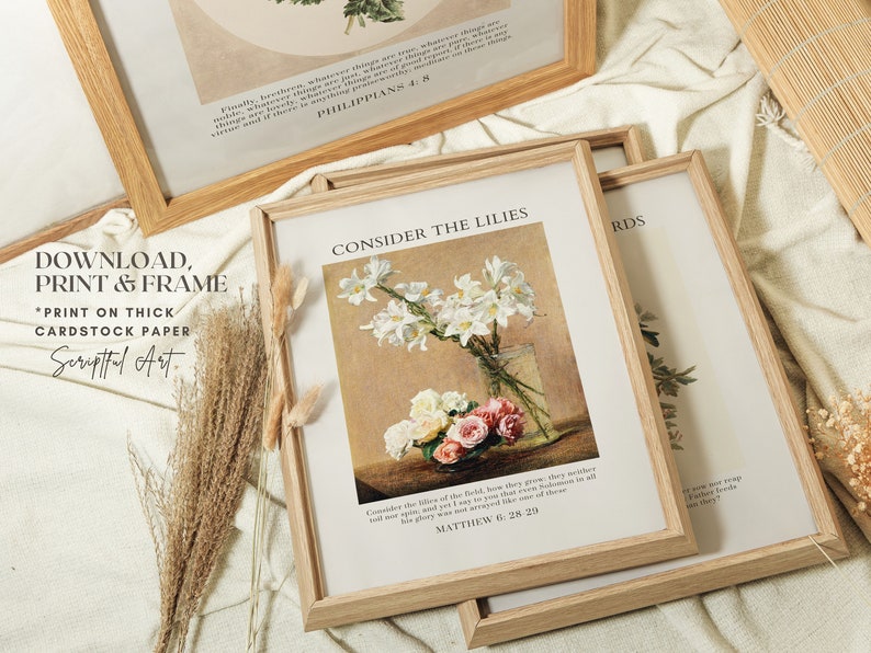 May include: Three framed prints with white backgrounds and brown wood frames. The top print has the text 'Finally, brothers, whatever things are true, whatever things are noble, whatever things are just, whatever things are pure, whatever things are lovely, whatever things are of good report, if there is any virtue and if there is anything praiseworthy - think on these things.' and 'PHILIPPIANS 4:8'. The middle print has a painting of white lilies in a vase and the text 'CONSIDER THE LILIES' and 'Consider the lilies of the field, how they grow; they neither toil nor spin, and yet I say to you that even Solomon in all his glory was not arrayed like one of these.' and 'MATTHEW 6:28-29'. The bottom print has the text 'RDS'.