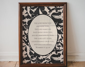 May include: A framed wall art piece featuring a dark brown wooden frame surrounding a print with a black and white bird pattern. In the centre, an oval area contains the text: THE LORD BLESS YOU AND KEEP YOU; THE LORD MAKE HIS FACE SHINE UPON YOU, AND BE GRACIOUS TO YOU; THE LORD LIFT UP HIS COUNTENANCE UPON YOU, AND GIVE YOU PEACE. NUMBERS 6: 24-26.