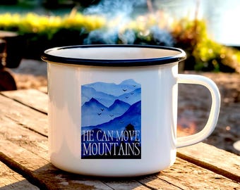 Peut inclure: Mug de camping en émail blanc avec un bord noir. Le mug présente une scène de montagne en aquarelle bleue avec le texte "He can move mountains".