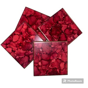 May include: Set of four red and black square coasters with a marbled design. The coasters have a dark brown border.