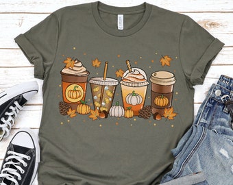 Puede incluir: Una camiseta verde con un gráfico de cuatro bebidas de café con temática otoñal con calabazas, hojas y piñas. El texto "Army" es visible en la parte inferior de la imagen.