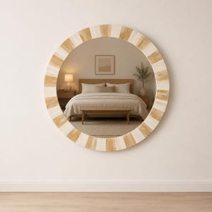 May include: A circular mirror with a decorative frame featuring a striped pattern in light and medium tones. The mirror reflects a bedroom scene, including a bed and bedside tables. The frame's diameter is approximately 76 cm.