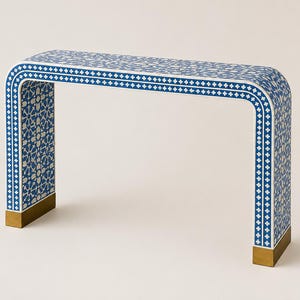 Könnte beinhalten: Eine Konsole mit blau-weißem Muster und geschwungenem Design. Der Tisch hat ein geometrisches Muster und goldfarbene Akzente an der Basis der Beine. Die Abmessungen des Tisches betragen ca. 122 cm lang, 36 cm breit und 76 cm hoch.