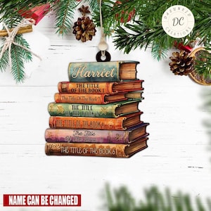 May include: A personalized Christmas ornament featuring a stack of six books with the name "Harriet" on the top book. The books have various titles, including "The Title of the Book 1", "The Title of the Book 2", and so on. The ornament is made of wood and has a rustic, vintage look.