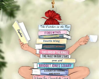 May include: A colorful Christmas ornament featuring a woman sitting cross-legged with a stack of books on her lap. The books have titles like "The Catcher in the Rye", "Bridget Jones's Diary", and "The Lost Book Shop".