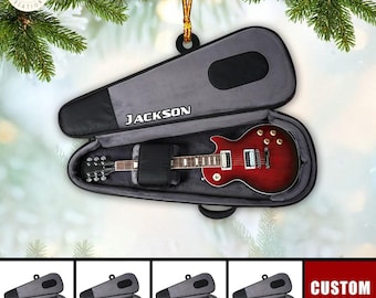 Może przedstawiać: Czerwona gitara elektryczna w szarym futerału na gitarę z napisem "JACKSON" nadrukowanym na futerału. Futerał wisi na sznurku i jest otoczony zielonymi gałązkami sosny. Pod głównym obrazem znajdują się cztery mniejsze obrazy przedstawiające futerał na gitarę z różnokolorowymi gitarami w środku.