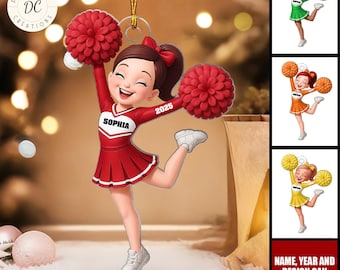 May include: A red cheerleader ornament with the name "SOPHIA" and the year "2025" on the uniform. The ornament features a smiling cheerleader with red pom-poms and a matching uniform. The text "NAME, YEAR AND DESIGN CAN BE CHANGED" is also visible.
