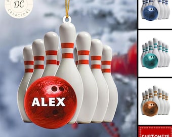 Puede incluir: Adorno navideño con temática de bolos. Presenta bolos blancos con rayas rojas y una bola de bolos roja con el nombre "ALEX". El adorno está suspendido por una cuerda dorada. Se muestran combinaciones adicionales de bolas y bolos.