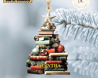Puede incluir: Un adorno de árbol de Navidad de madera con forma de pila de libros con una estrella dorada en la parte superior. El adorno está decorado con adornos rojos y dorados y el nombre "JACINTHA" está escrito en la parte inferior.