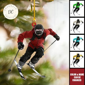 Puede incluir: Adorno navideño personalizado con un esquiador con chaqueta roja, pantalones negros y casco negro con el nombre "JACK". El adorno tiene una cuerda dorada y el texto "COLOR & NAME CAN BE CHANGED".
