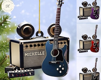 Może przedstawiać: Niebieski gitarę akustyczną z czarnym pickguadem i chromowanymi elementami. Gitara wisi na złotej sznurku i znajduje się obok brązowego wzmacniacza z napisem "Michelle". Po lewej stronie wzmacniacza znajdują się dwa czarne głośniki i czarny pedał.