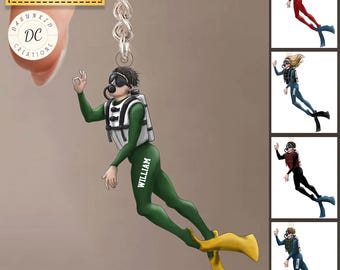 May include: A keychain featuring a diver in a green wetsuit with the name "WILLIAM" on the leg. The diver is wearing a diving mask and a white buoyancy compensator. The keychain has a silver chain and the text "Color & Name can be changed".