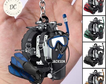 May include: A scuba diving keychain featuring a black tank, blue flippers, and a diving mask with the name "Jackson." The keychain includes a silver chain and a "Personalized Design" banner. Additional color variations are shown.