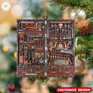 May include: A wooden Christmas ornament shaped like a toolbox filled with tools. The toolbox is brown with gold accents and has the name "Micheal" on the front.