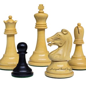 May include: A collection of wooden chess pieces, including a queen, king, knight, bishop, and pawn. The pieces are light-colored wood with a natural finish, except for the black pawn. The knight piece has a detailed horse head design. The logo "Antique Chess Crafts" is visible.