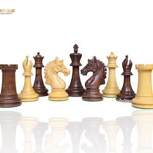 Peut inclure: Un ensemble de pièces d'échecs en bois sculpté, comprenant des tours, des fous, des cavaliers, une reine et un roi, dans des tons de marron et de crème. L'ensemble est présenté sur un fond blanc. Le logo "Antique Chess Crafts" est visible en haut à gauche.