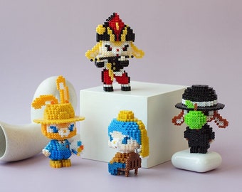 May include: Four colorful, pixelated figurines, each with a unique design, stand on a white surface. The figurines are made of small, colorful beads. The text "The Artist" is written in white on a light purple background.