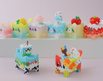 May include: A collection of colourful, pixelated animal figurines. The figurines are made of small beads and feature various designs, including a strawberry, a cupcake, a teacup, and a paintbrush.