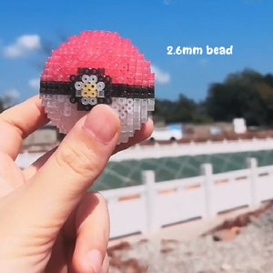May include: A red and white Pokeball made with 2.6 mm beads. The Pokeball is made with small, square beads that are arranged in a sphere shape. The Pokeball is a popular character from the Pokemon franchise.