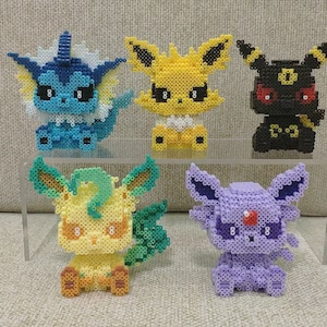 Könnte beinhalten: Fünf verschiedene Pokémon-Charaktere aus bunten Perlen. Die Charaktere sind Eevee, Vaporeon, Jolteon, Flareon und Umbreon.