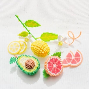 May include: A set of beaded fruit and flower charms, including a lemon, avocado, grapefruit, and a lemon blossom branch. The charms are made of colorful plastic beads.