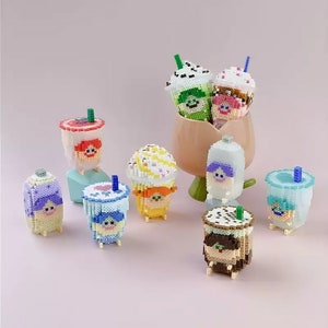 Op de afbeelding: Een verzameling van acht kleurrijke, miniatuur, geperde figuren die mensen voorstellen die verschillende stijlen bubble tea bekers dragen. De figuren zijn gemaakt van kleine, kleurrijke kralen en hebben schattige gezichten.
