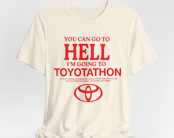 May include: A white t-shirt with the text "You can go to hell I'm going to Toyotathon" in red. The text is accompanied by the Toyota logo in red. The text below the logo reads "With 0% annual APR on select SUVs, sedans, and trucks for up to 72 months for well qualified customers."