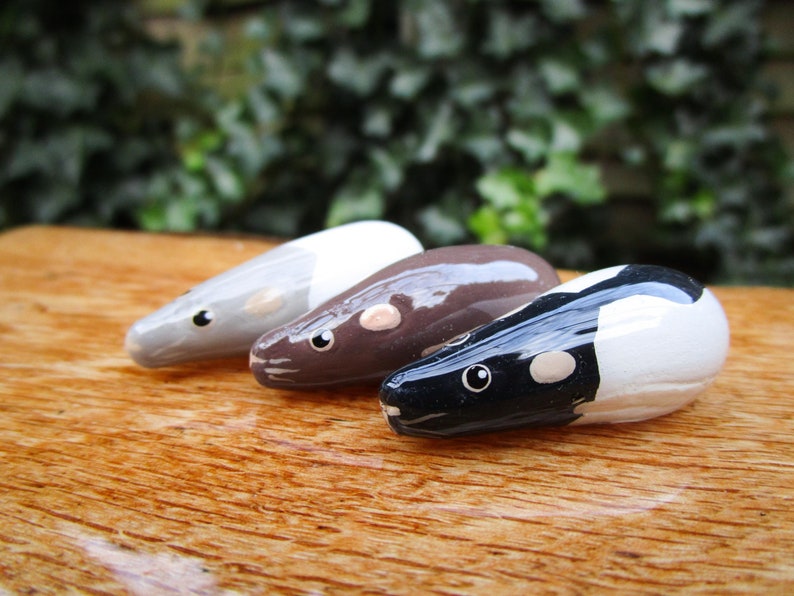 May include: Three ceramic rat figurines, each painted in a different color scheme. The first rat is gray and white, the second is brown and white, and the third is black and white.