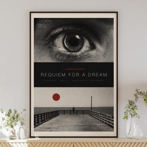 Könnte beinhalten: Gerahmtes Filmplakat für "Requiem for a Dream". Die obere Hälfte zeigt eine Nahaufnahme eines Auges in Schwarzweiß. Der mittlere Abschnitt enthält den Filmtitel und die Credits. Der untere Teil zeigt einen Steg mit roter Sonne.