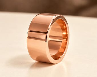 Könnte beinhalten: Ein breiter Ring aus poliertem Roségold mit einer glatten, reflektierenden Oberfläche. Der Ring zeichnet sich durch eine dicke, massive Konstruktion mit einem Hochglanz-Finish aus, das das Licht einfängt und klare Glanzlichter erzeugt.