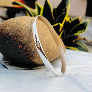 Può includere: Un braccialetto rigido in argento con una finitura liscia e lucida.