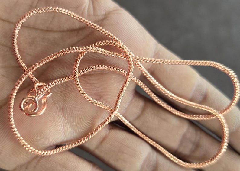 Puede incluir: Un collar de cadena de oro rosa con cierre de mosquet&oacute;n. La cadena est&aacute; hecha de un dise&ntilde;o de cuerda trenzada.