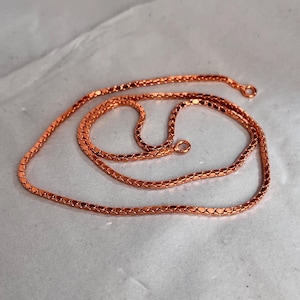 Può includere: Una collana a catena di rame con un design a catena a maglie quadrate. La catena è lunga circa 50 cm e ha una chiusura a moschettone.